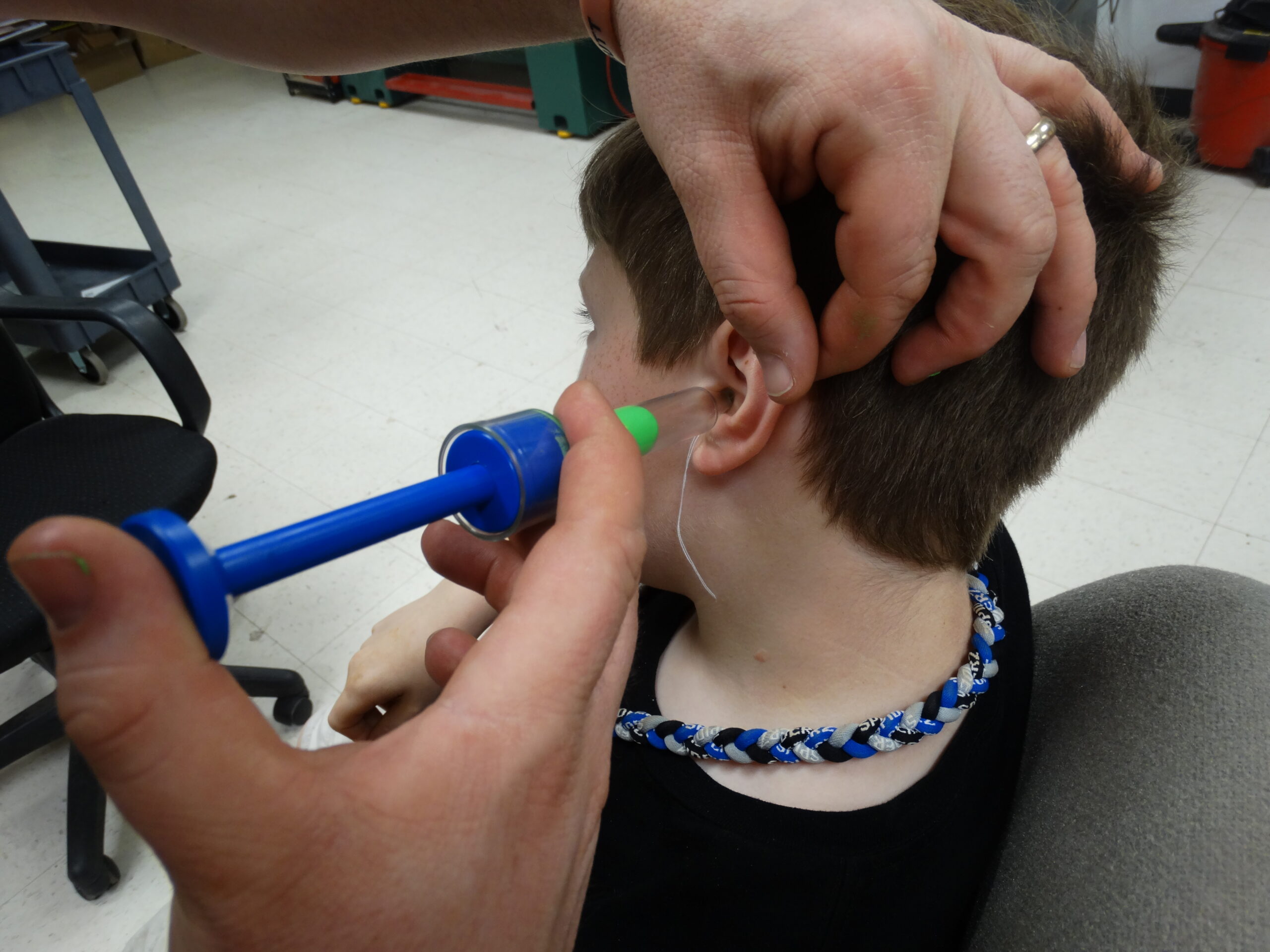 Child getting custom ear plugs for joining his dad at the range